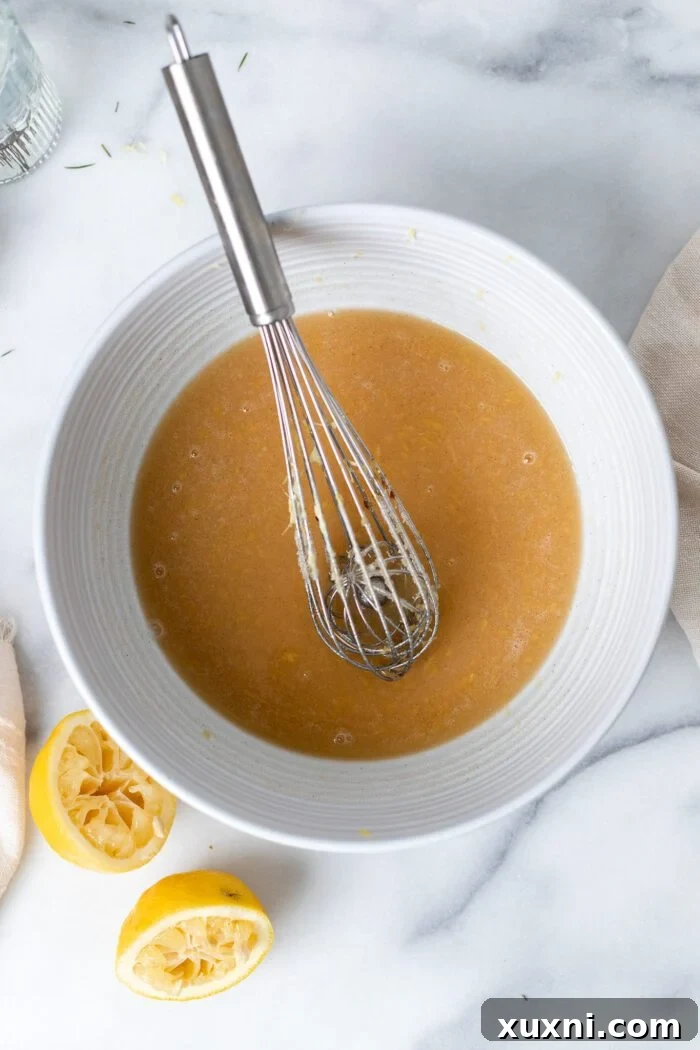 Mixing bowl with wet ingredients for vegan lemon pound cake batter, showcasing a smooth, creamy mixture.