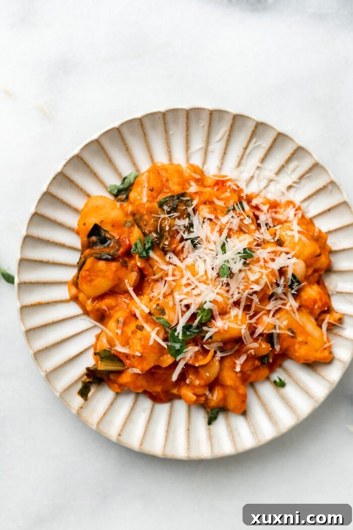 25-Minute No-Boil Vegan Cheesy Baked Gnocchi with Beans 13 A close-up of a plate of cheesy vegan baked gnocchi, garnished with fresh basil.