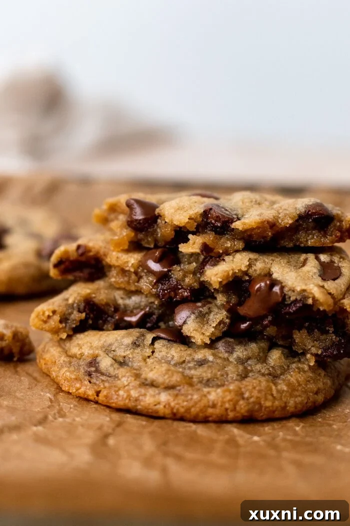 A stack of several perfectly baked vegan chocolate chip cookies, showcasing their golden-brown edges and soft centers.