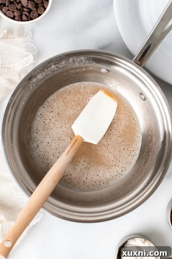 Close-up of vegan butter browning in a saucepan over medium heat, showing the initial melting stage.