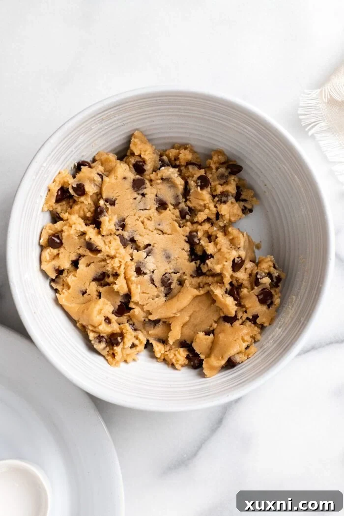 Chocolate chip cookie dough with visible chocolate chunks in a mixing bowl, ready for chilling.