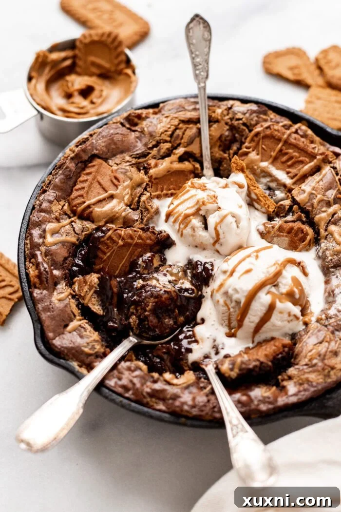 Warm, gooey vegan Biscoff Brownies in a cast iron skillet, perfect for sharing.