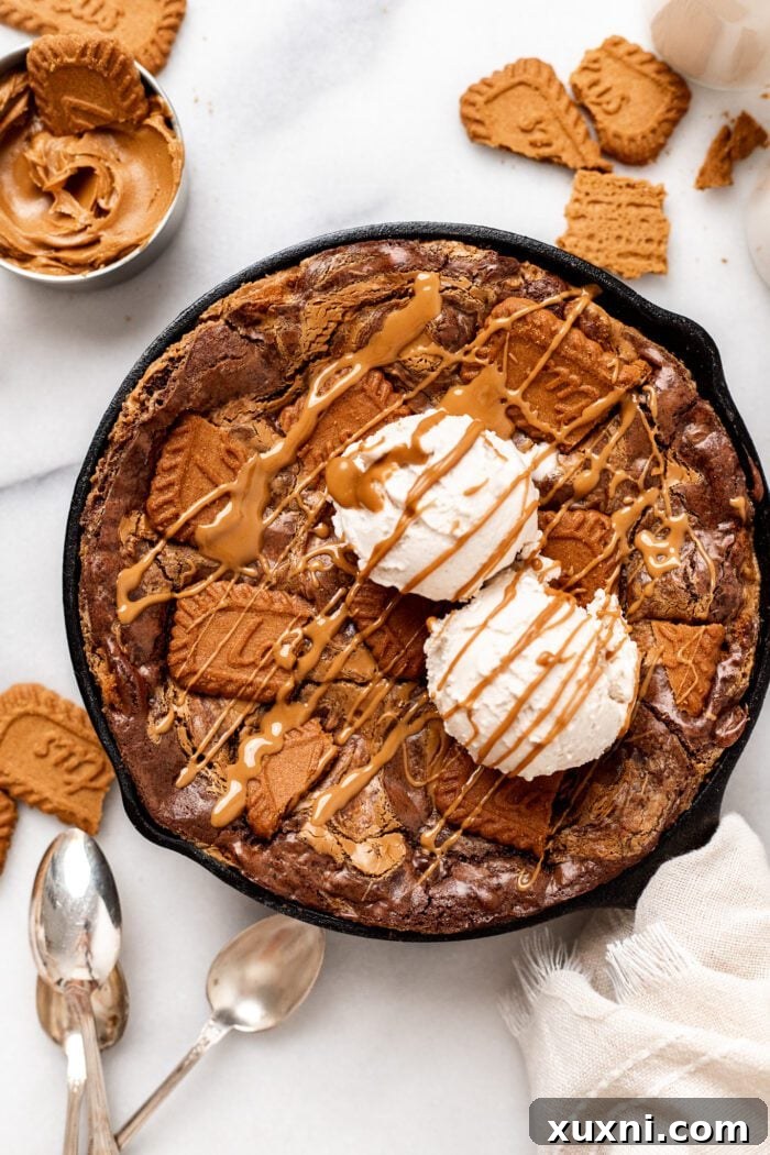 Baked vegan Biscoff Brownies in a skillet with a spoon, ready to serve.