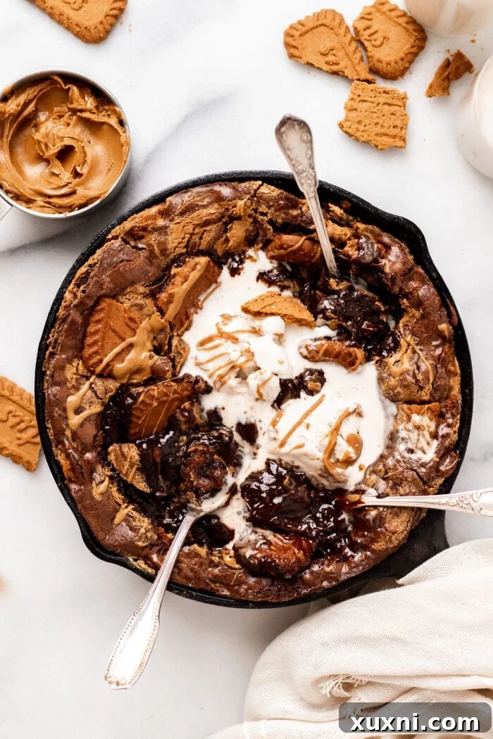 Three spoons digging into a rich vegan Biscoff Brownie skillet, emphasizing its shareability.