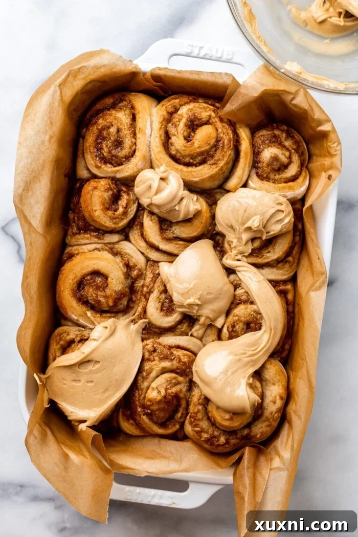 Spreading peanut butter frosting over warm cinnamon rolls