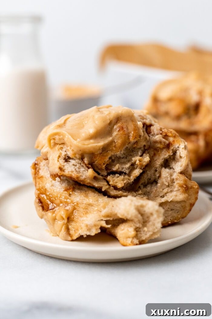 A close-up of a vegan banana bread cinnamon roll with a bite taken out, showing the swirl
