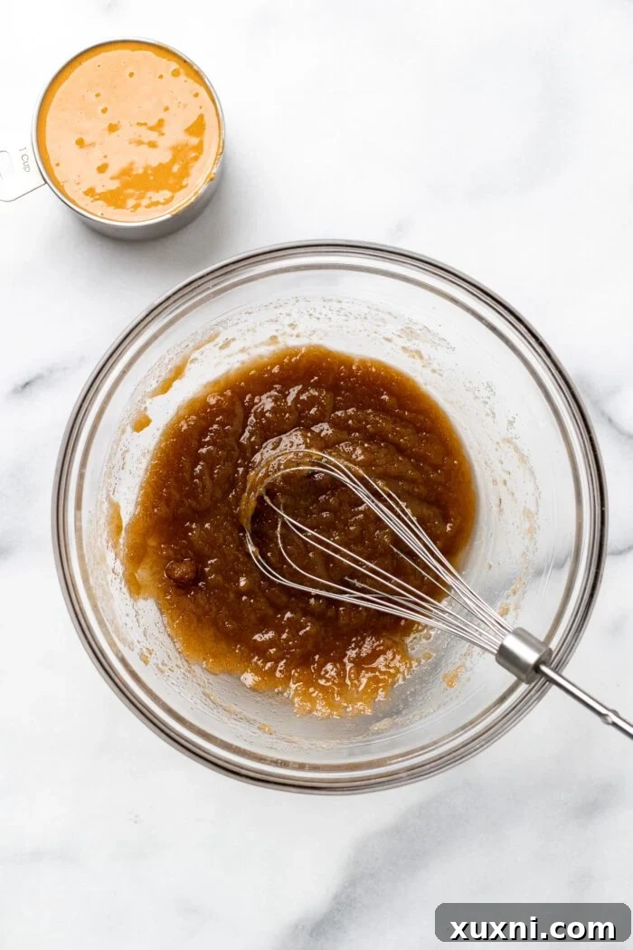 Whisking the melted vegan butter, brown sugar, and granulated sugar in a large bowl