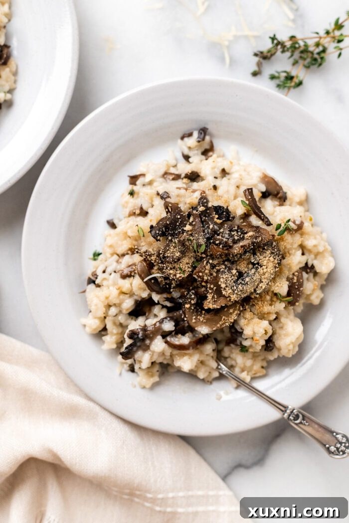 Plate of creamy vegan risotto with sautéed mushrooms, garnished with fresh herbs.