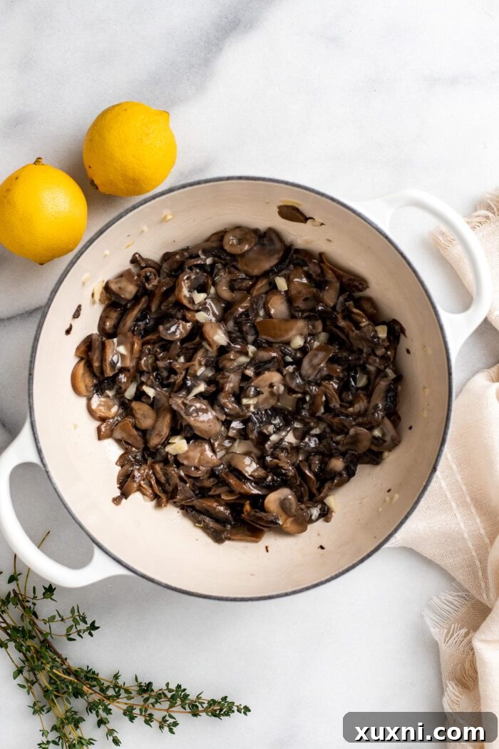 Sliced mushrooms and minced garlic sautéing in melted vegan butter in a Dutch oven.