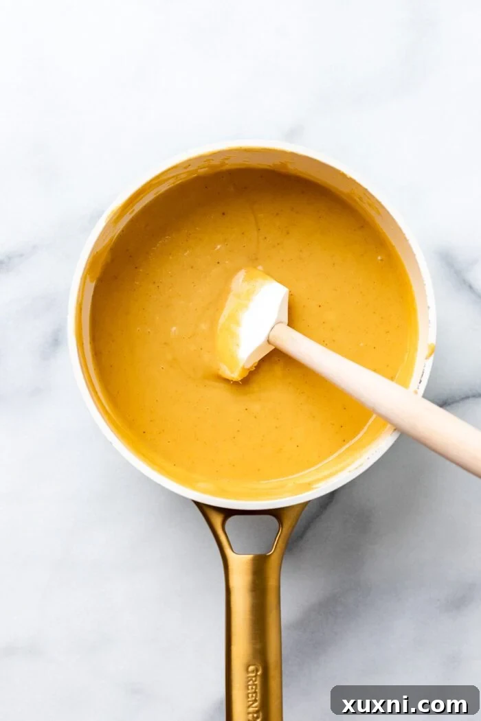vegan queso cooking in a saucepan, thickening on the stove