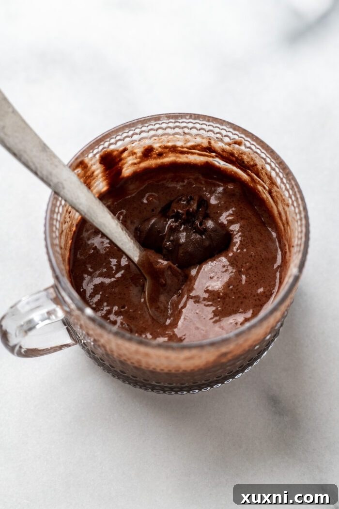 A spoonful of vegan Nutella placed on top of the mug cake batter