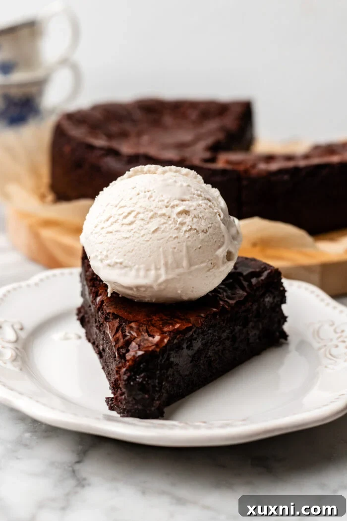 A perfectly sliced vegan flourless chocolate cake on a plate, showcasing its rich, fudgy interior and crinkly top.