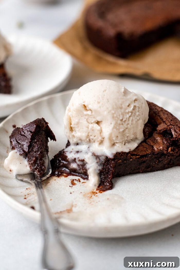 A delicious slice of vegan flourless chocolate cake with a bite taken out, emphasizing its moist and luxurious interior.