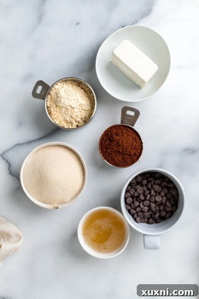 The six essential vegan flourless chocolate cake ingredients laid out on a marble surface: vegan butter, chocolate, aquafaba, chickpea flour, cocoa powder, and sugar.