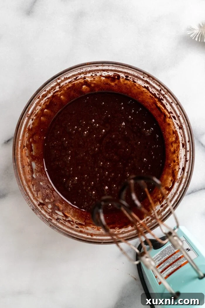 The melted chocolate and butter mixture being poured into the aquafaba and sugar batter.