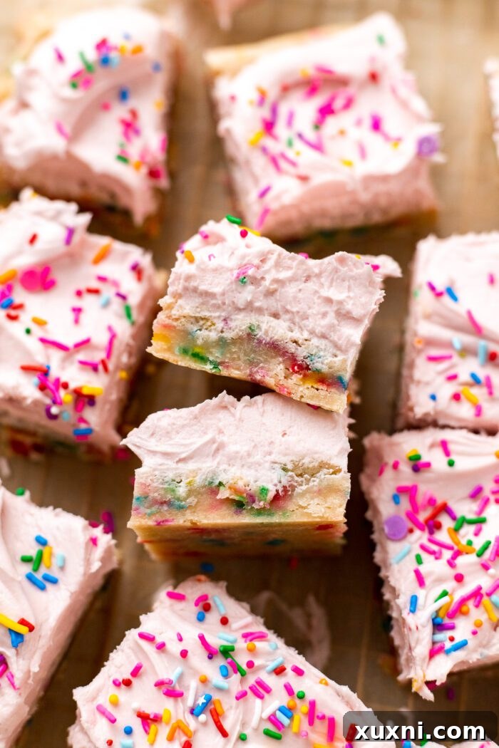 A tray of unfrosted vegan sugar cookies with sprinkles, cooling on parchment paper after baking.