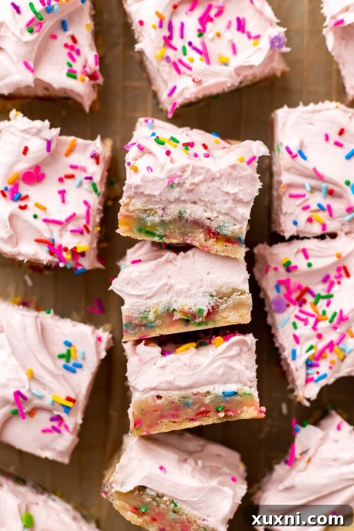 Close-up of freshly baked vegan sugar cookie bars on parchment paper, ready for frosting and slicing, highlighting their golden edges.