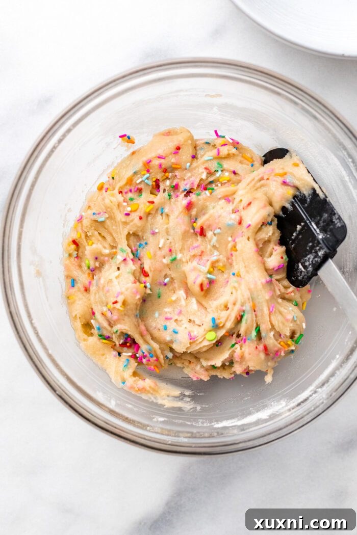 Sprinkle funfetti cookie dough in a bowl, with sprinkles evenly distributed throughout the mixture.