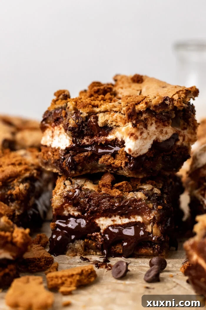 Stacked gooey vegan s'mores cookie bars, showcasing the melted chocolate and fluffy marshmallow layers