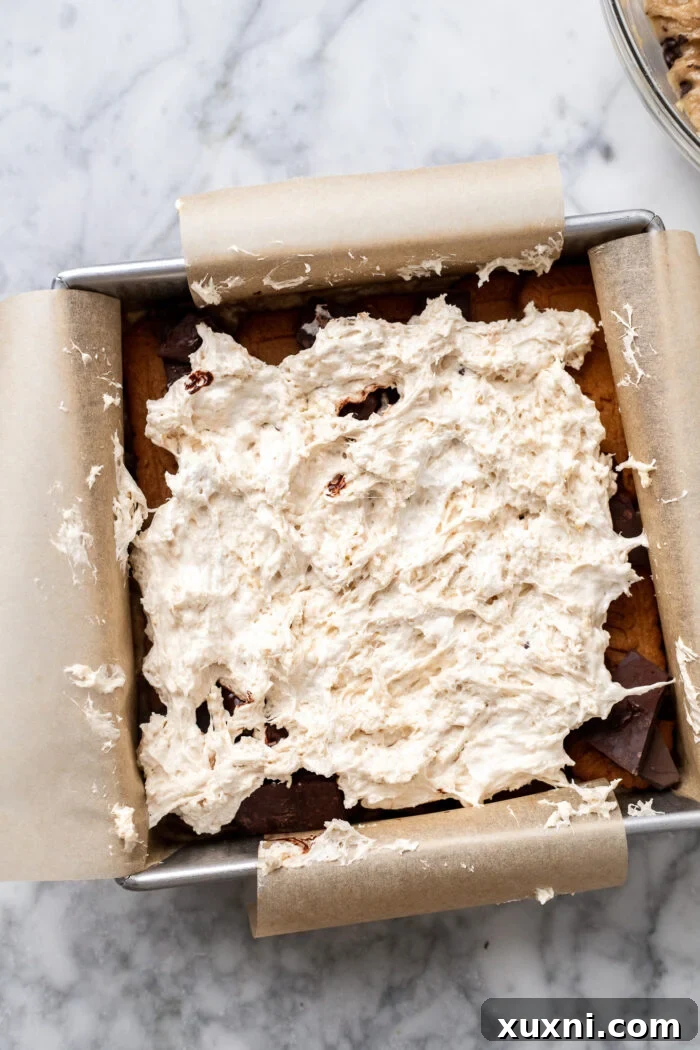 Assembling the layers of vegan s'mores cookie bars in a baking pan