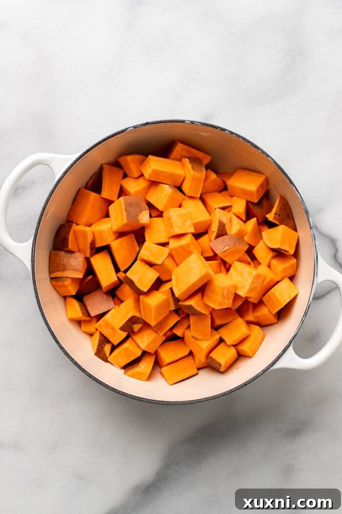 Uniformly cubed sweet potatoes placed in a Dutch oven, ready for seasoning and roasting.