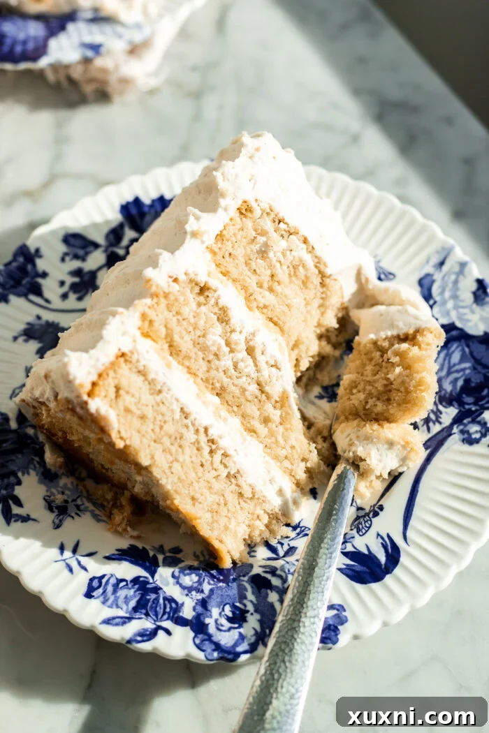 A perfectly sliced piece of moist vegan vanilla cake on a white plate, showcasing its fluffy texture.