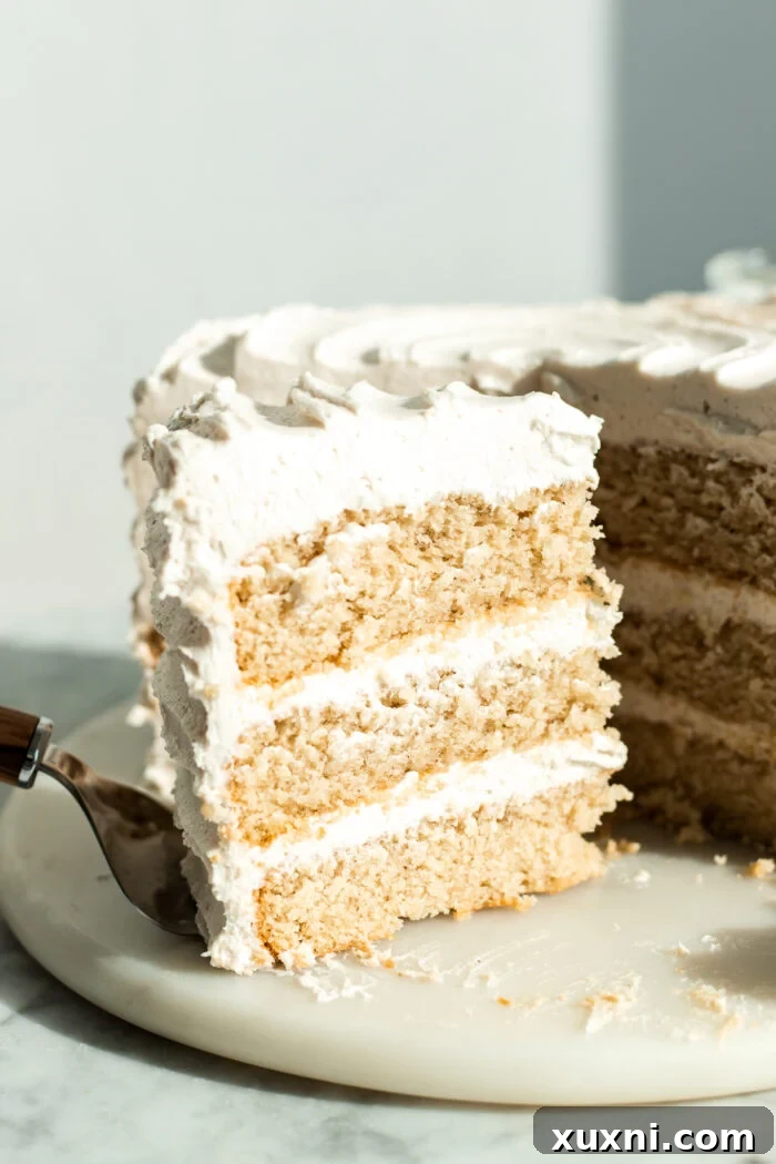 A slice of vegan vanilla cake on a vibrant blue plate, garnished with a single fresh blueberry.