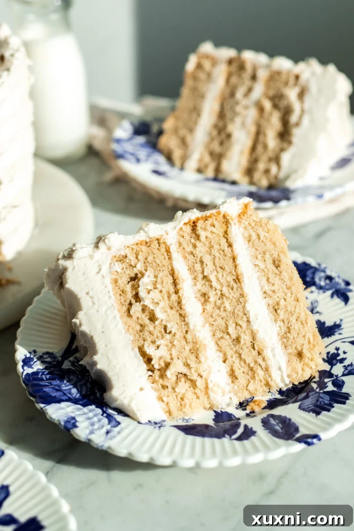 A slice of elegant vegan vanilla cake on a marble surface, adorned with edible flowers.