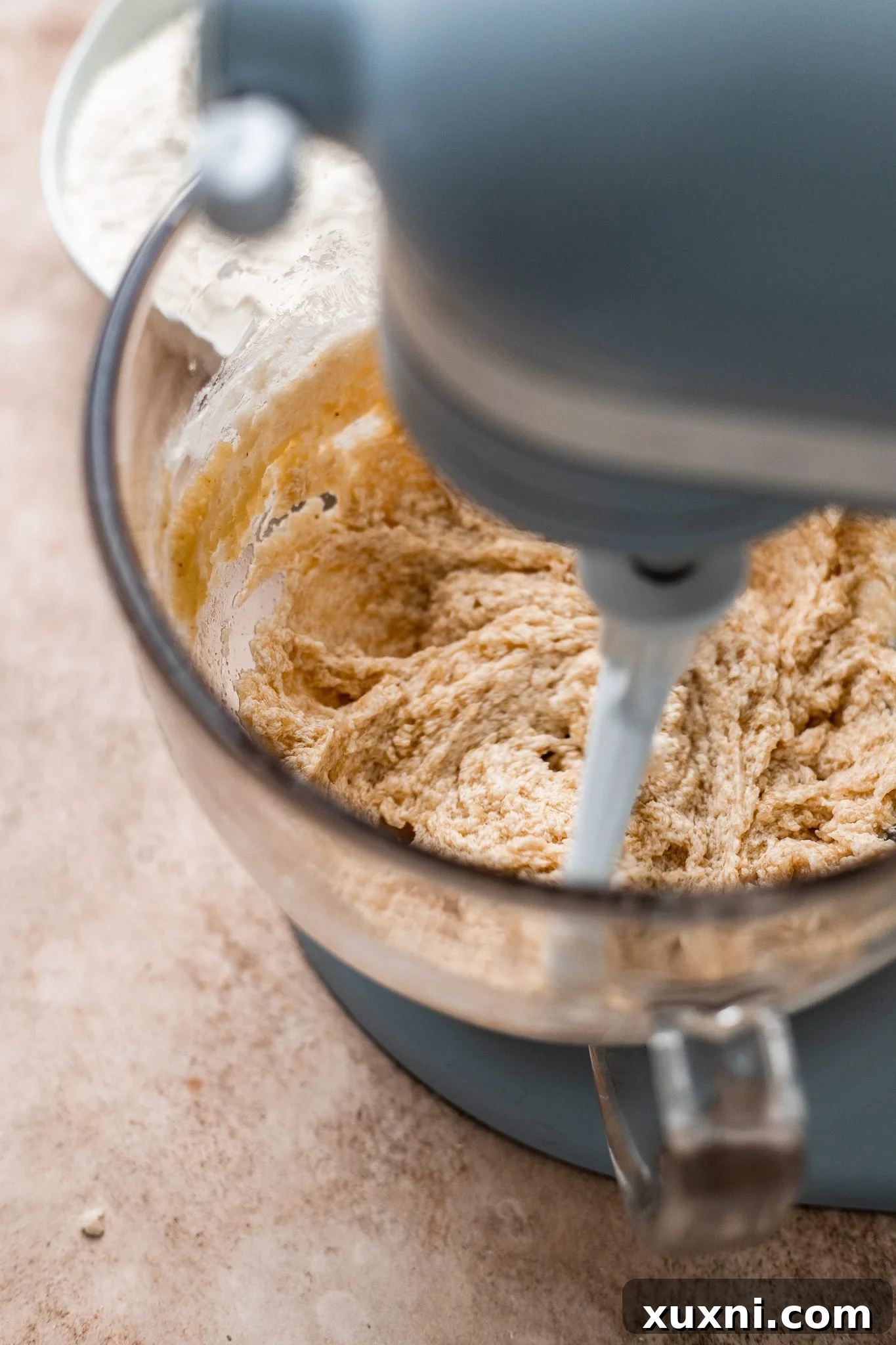 Adding dry ingredients to the wet mixture to create the vanilla cake batter.