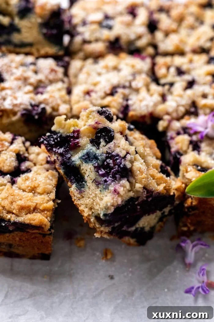 Slice of vegan blueberry buckle on parchment paper with delicate flowers