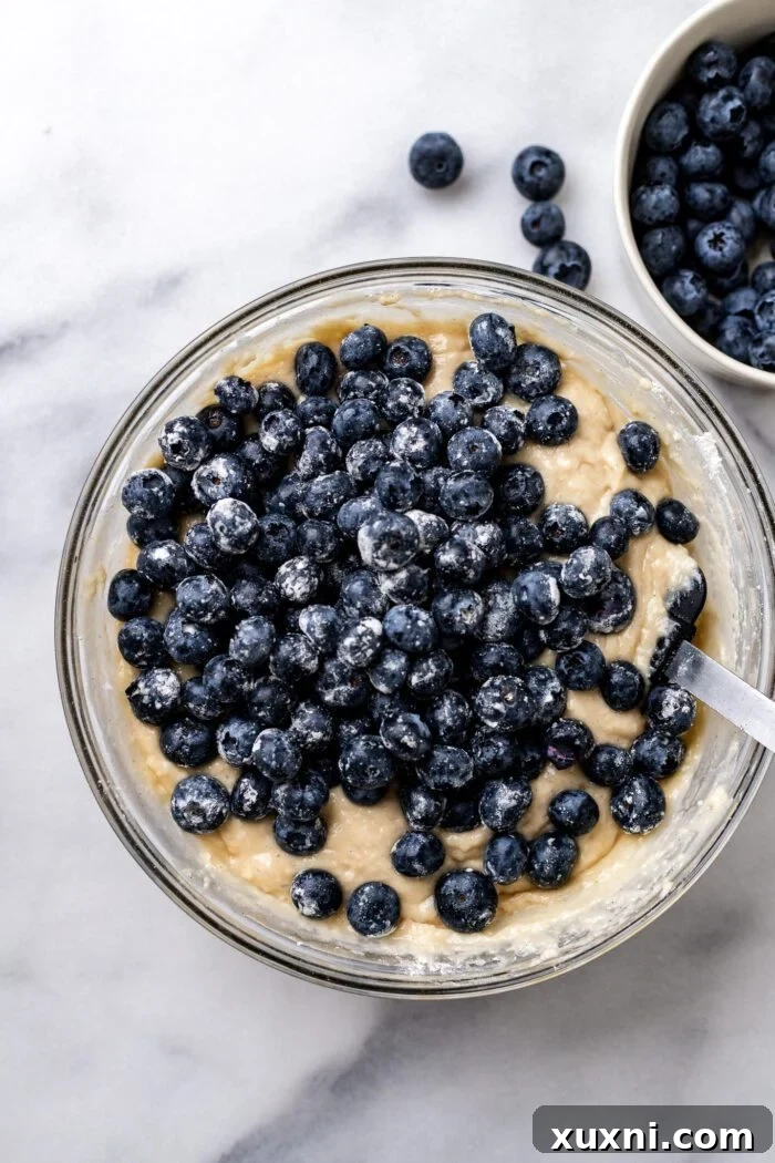 Floured blueberries being added to blueberry buckle batter