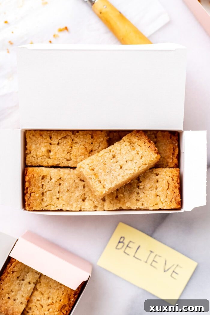 Close-up of golden-baked vegan shortbread biscuits, some already sliced, in a decorative box.