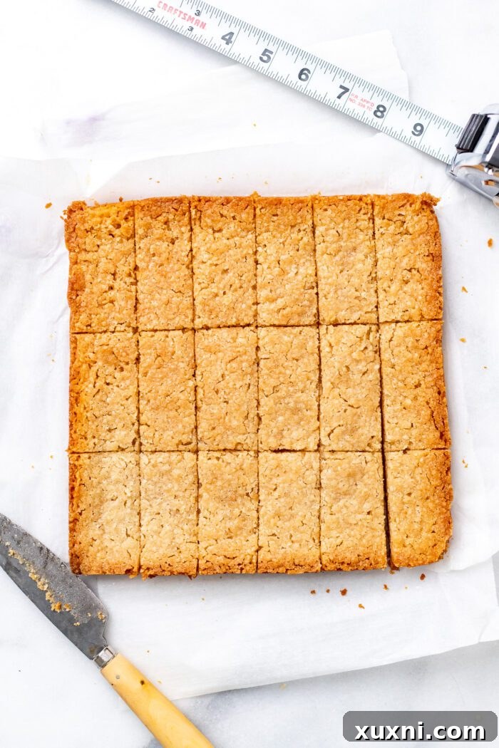 A large slab of cooled shortbread being sliced into individual biscuits using a ruler for precision.
