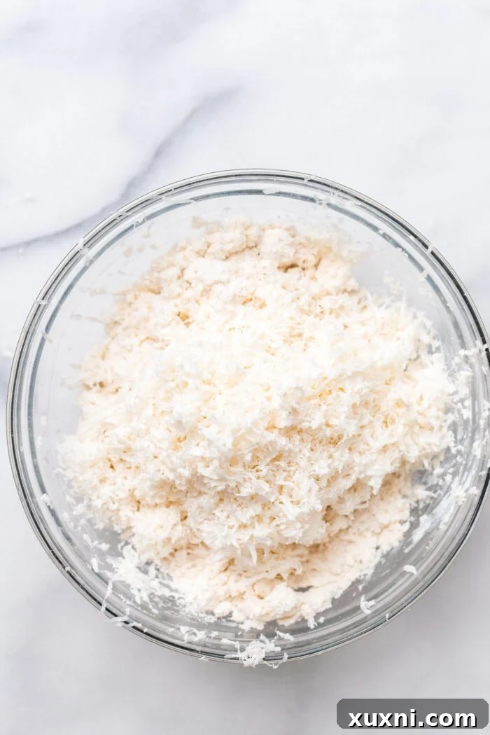 Grated frozen vegan butter added to the flour mixture in a bowl.