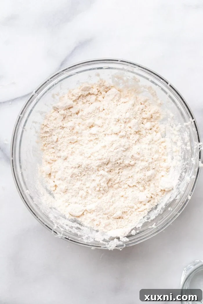 Hands gently rubbing flour and grated butter together for gluten-free puff pastry dough.