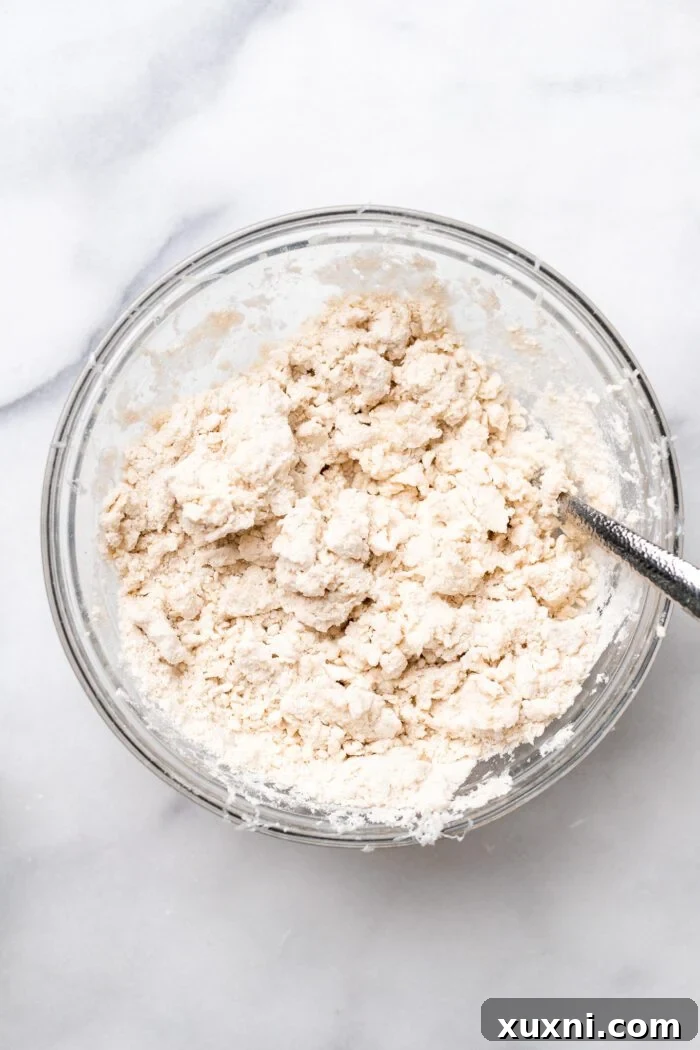 Adding ice cold water to the flour and butter mixture to form the dough.