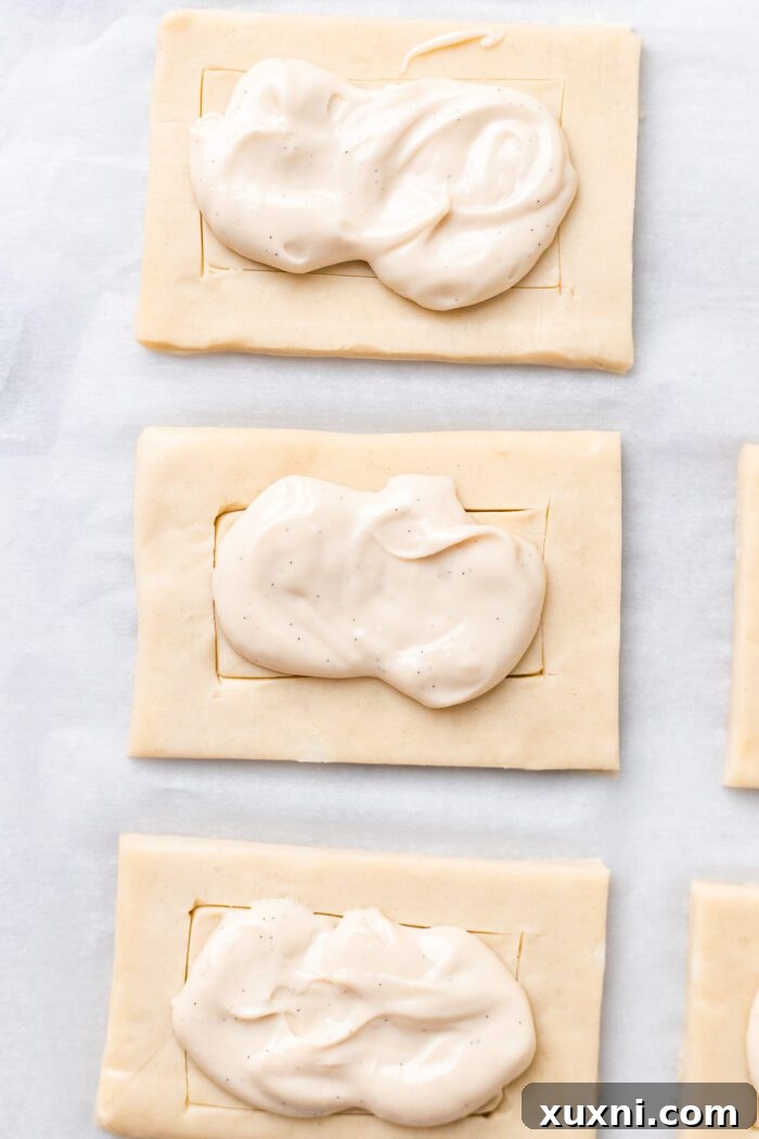 Applying creamy vegan cream cheese filling onto the scored puff pastry.