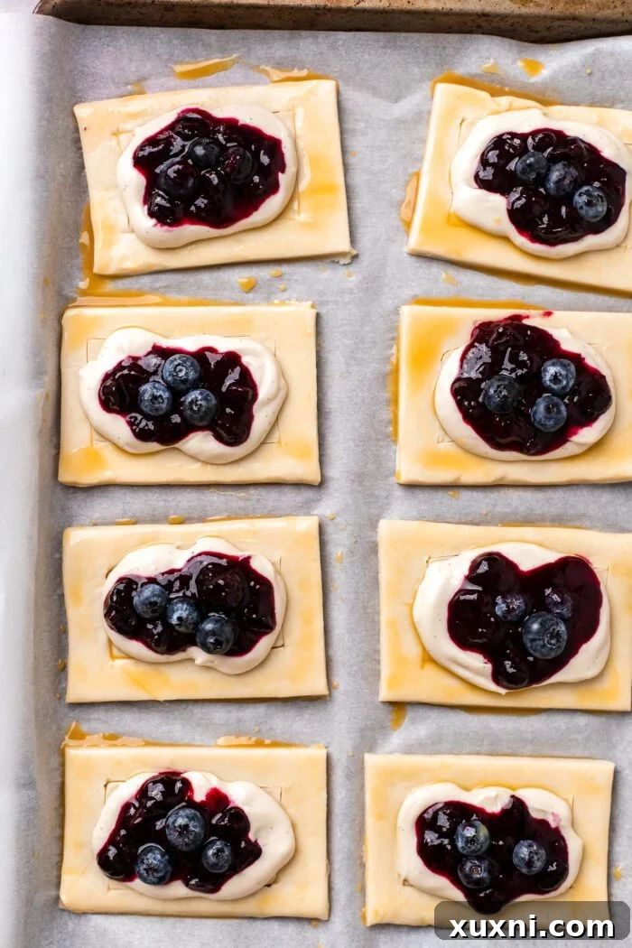 Puff pastry Danish pastries arranged on parchment paper before baking.