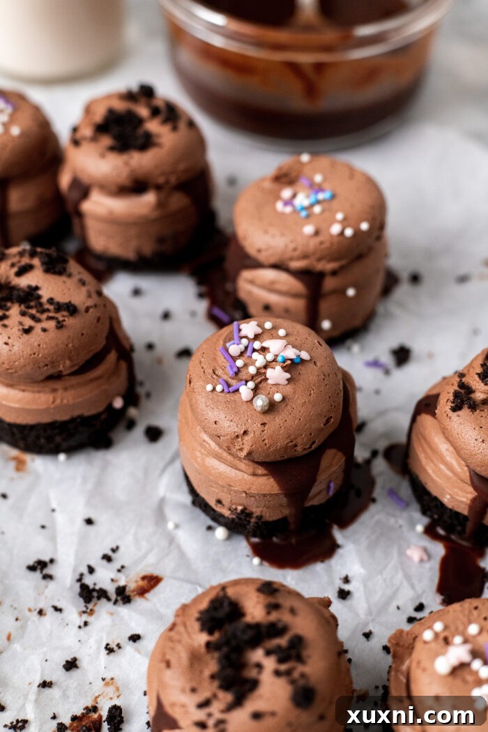 Easy No Bake Plant Based Chocolate Mini Cheesecakes 4 A trio of freshly made mini chocolate cheesecakes with cookie crumble topping, arranged beautifully on parchment paper.