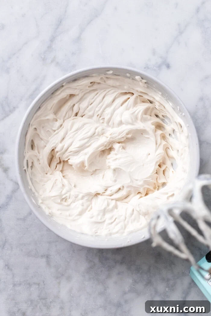 Easy No Bake Plant Based Chocolate Mini Cheesecakes 7 Cream cheese, dairy-free yogurt, and vegan whipping cream being mixed together in a bowl with a hand mixer, looking light and fluffy.