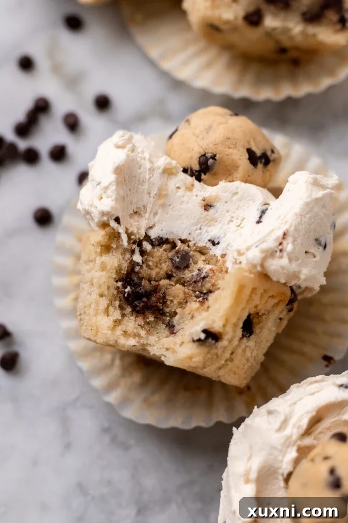 Close-up of a bitten cookie dough cupcake in its liner, showing the molten cookie dough center