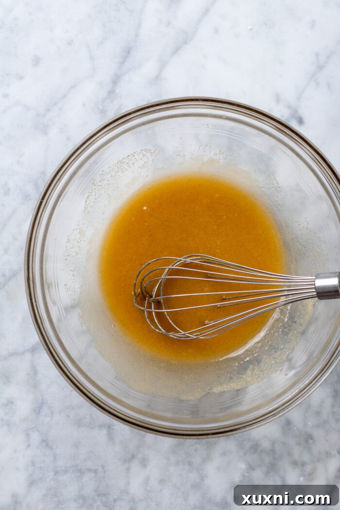 Wet ingredients for cupcakes whisked together in a mixing bowl until smooth and fully combined.