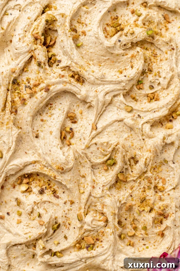 Vegan pistachio cream cheese frosting being spread onto a cooled cake.