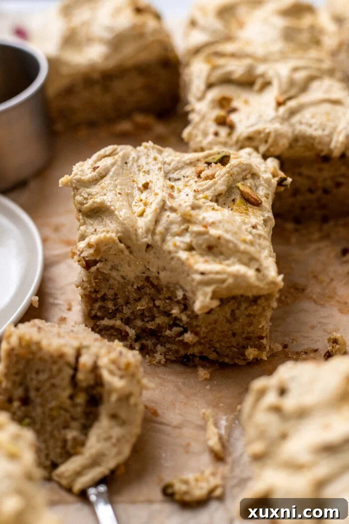 A beautifully sliced vegan pistachio cake, showcasing its vibrant green hue and fluffy texture.