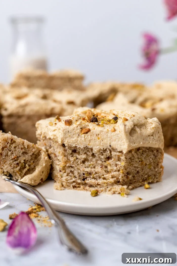 A perfectly sliced piece of vegan pistachio cake on a white plate, highlighting its tender crumb.
