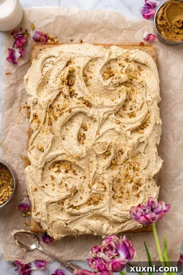 A freshly frosted vegan pistachio sheet cake on parchment paper, awaiting decoration.