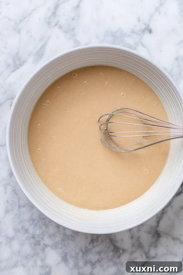 Wet ingredients for the cake, including melted vegan butter, yogurt, and extracts, whisked together in a bowl.