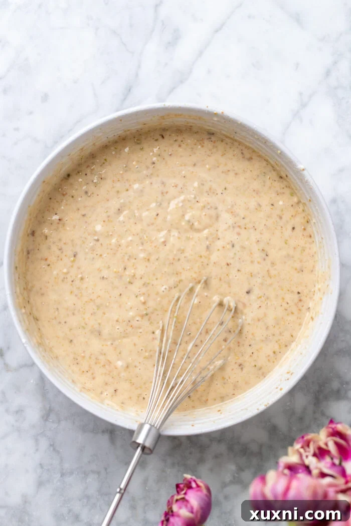 Pistachio cake batter in a large mixing bowl, showing its light green color.