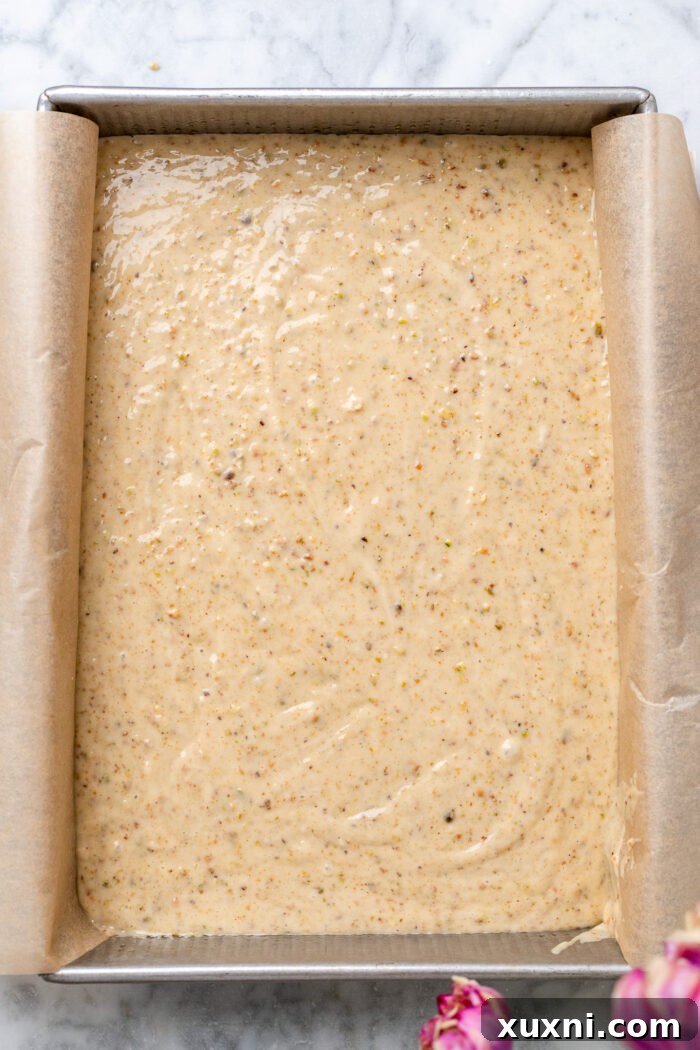 Pistachio cake batter poured into a prepared baking pan, ready for the oven.