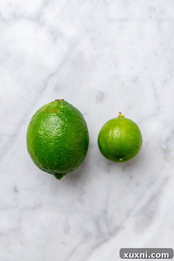 Comparison of a key lime and a regular lime on a marble surface